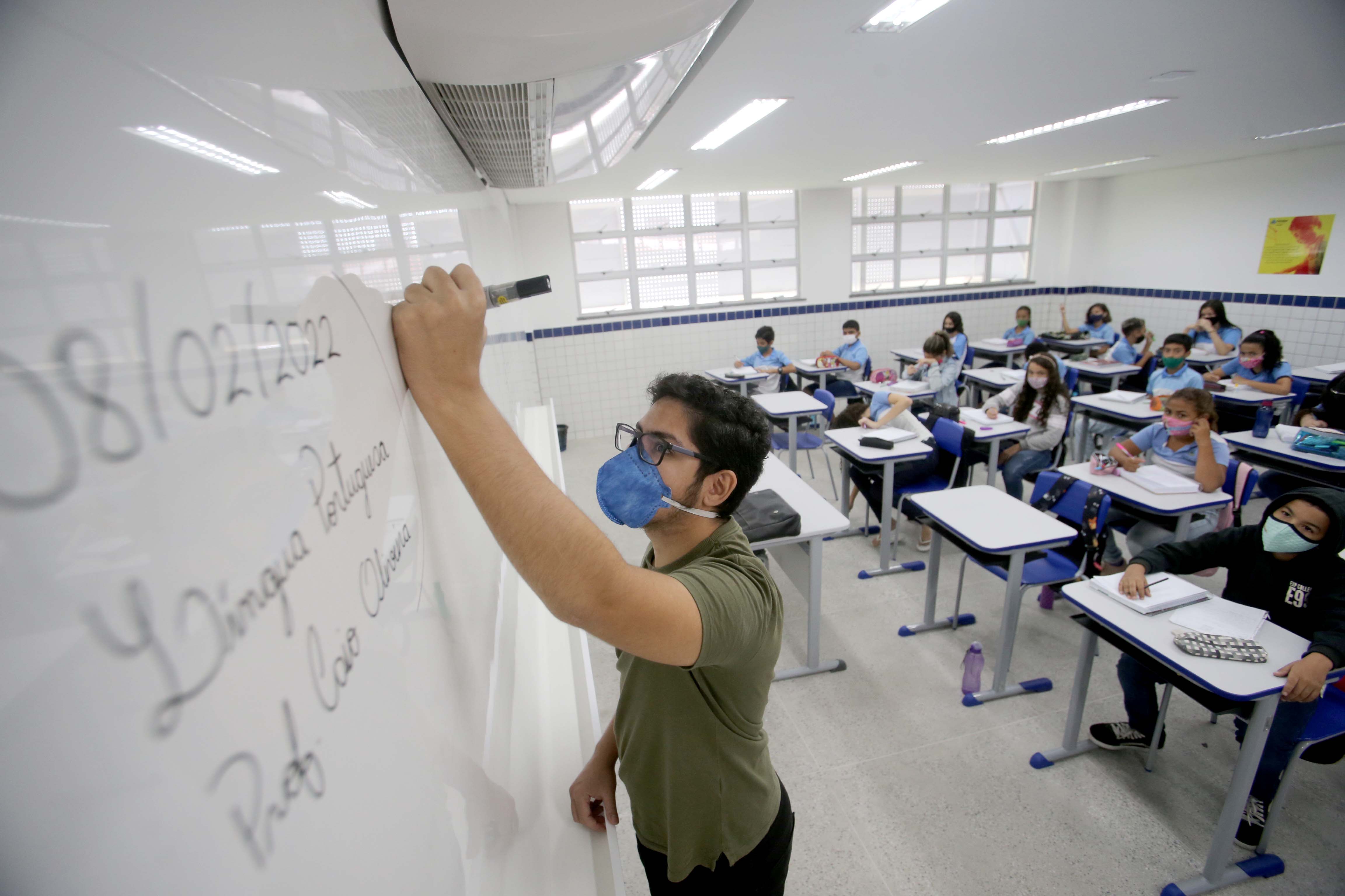 professor escreve no quadro branco e é observado pelos alunos